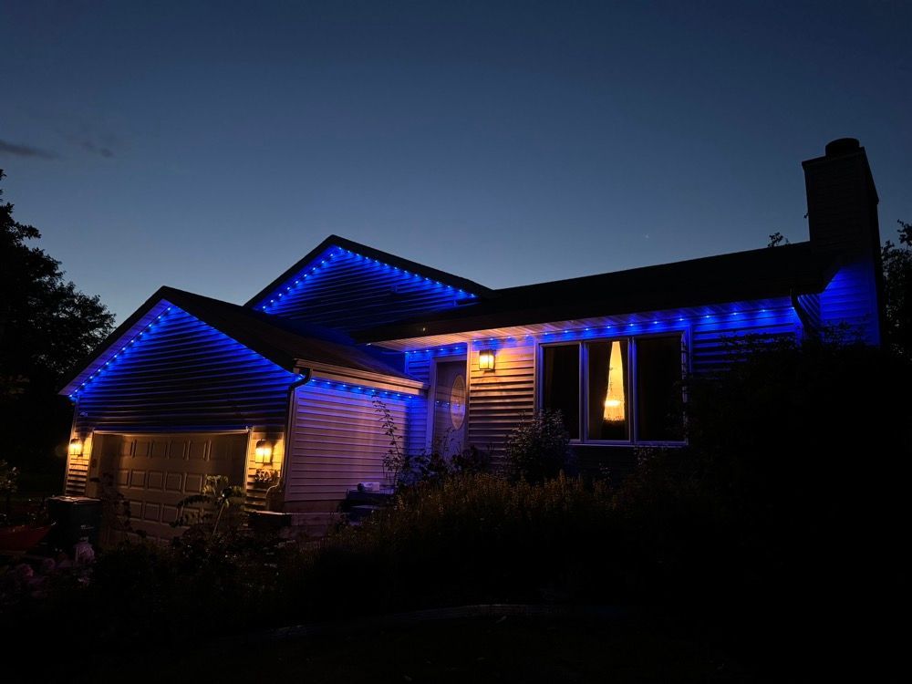 House at night with blue roof lights and warm porch lights against a dark sky