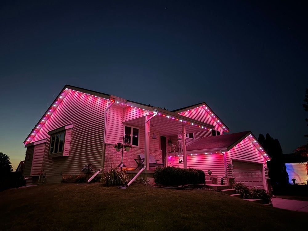 House outlined with pink holiday lights at dusk on a dark street