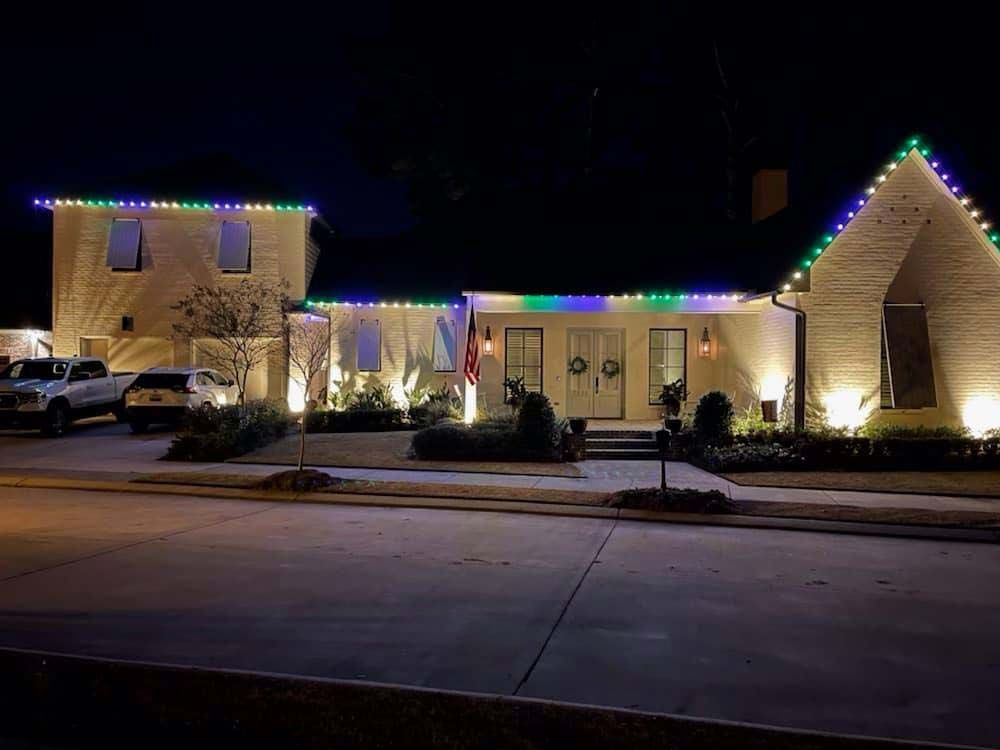 House at night with colorful Christmas lights and parked cars along the street