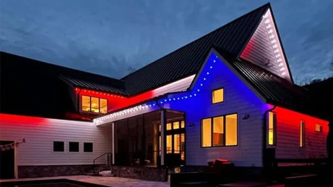 Modern house exterior at dusk with red, blue, and pink accent lighting