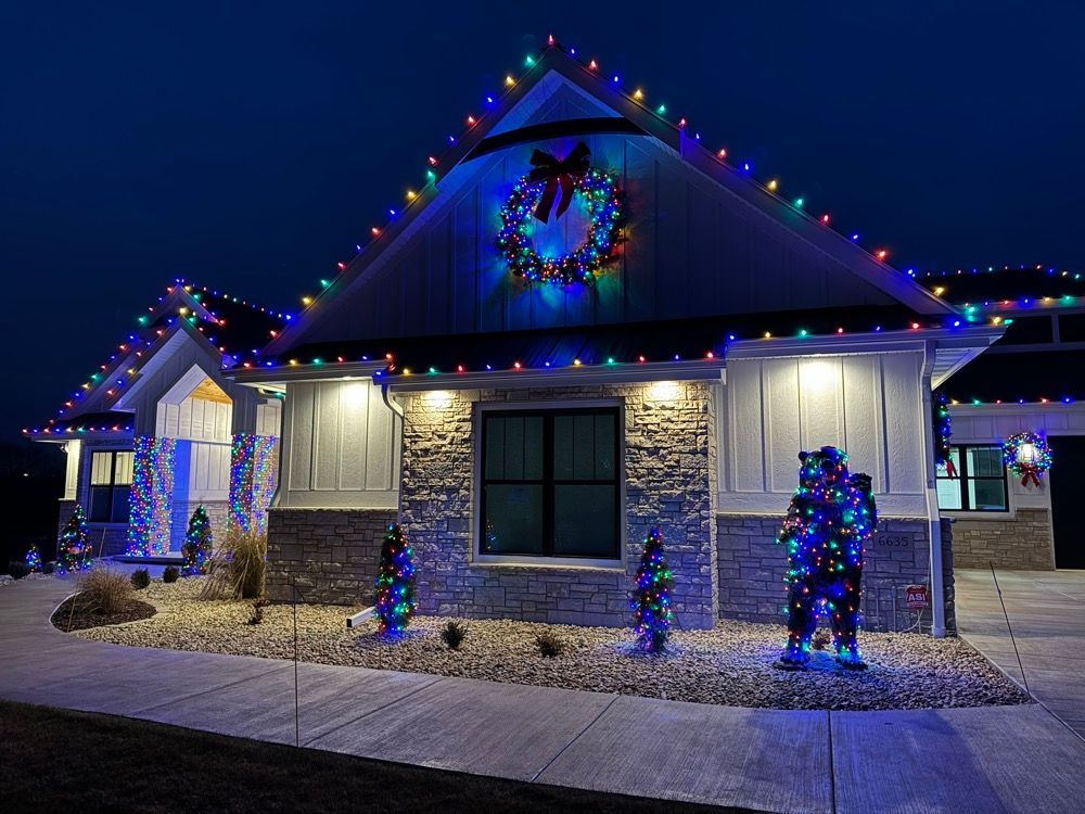 House decorated with colorful Christmas lights and blue-lit holiday figures at night