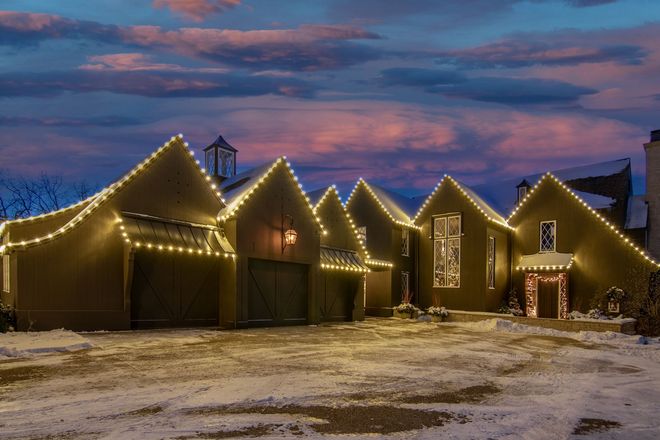 Snowy cabins outlined with warm string lights at dusk under a pink-blue sky