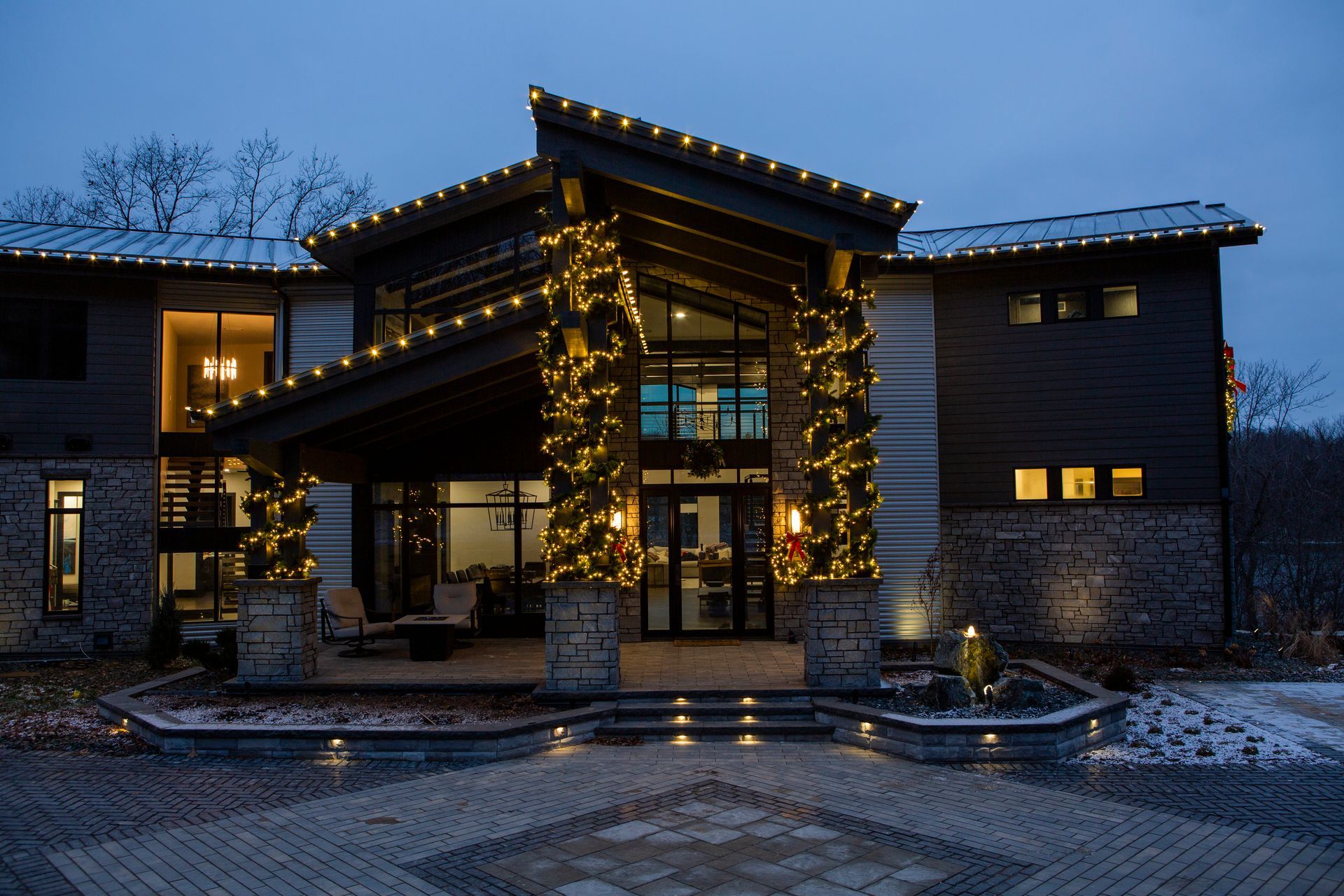 Modern house entrance lit with warm holiday lights at dusk