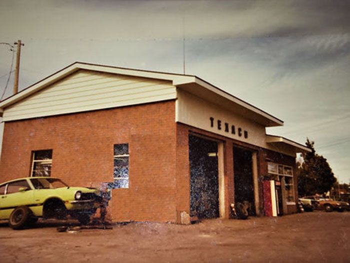 A yellow car is parked in front of a texaco gas station
