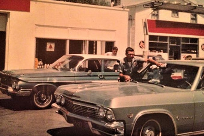 A man is sitting in a car next to two other cars