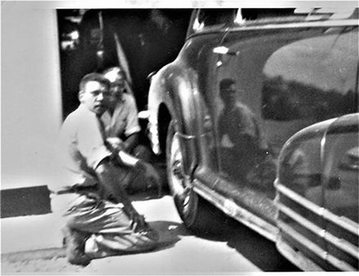 A black and white photo of two men working on a car