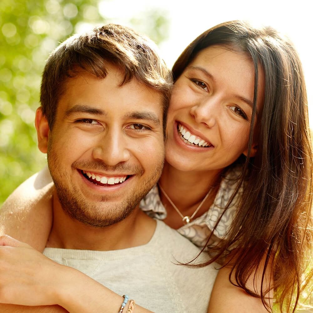 Smiling couple embracing outdoors in warm sunlight