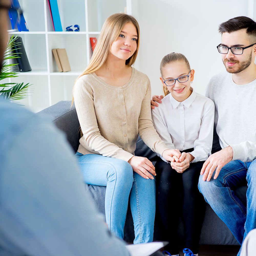 Three people sitting together in a bright counseling office, listening attentively.