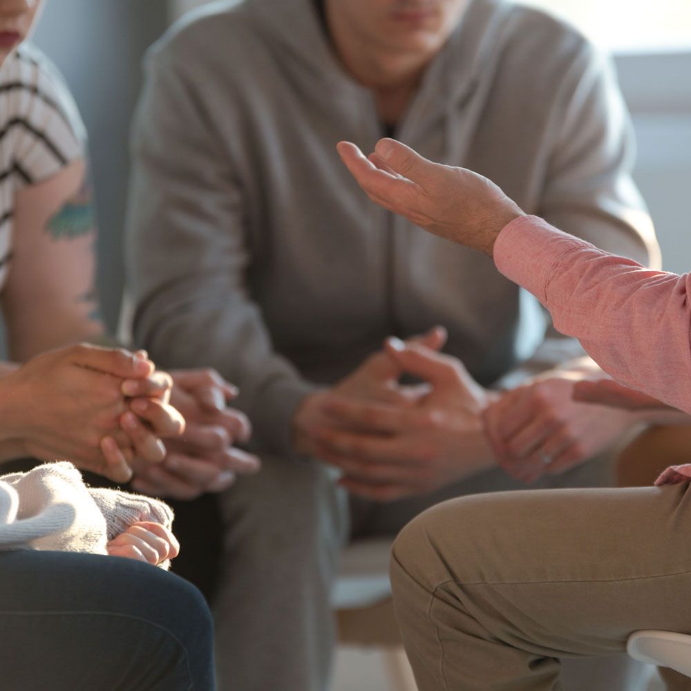 People in a small group discussion, with one person gesturing while others listen attentively.