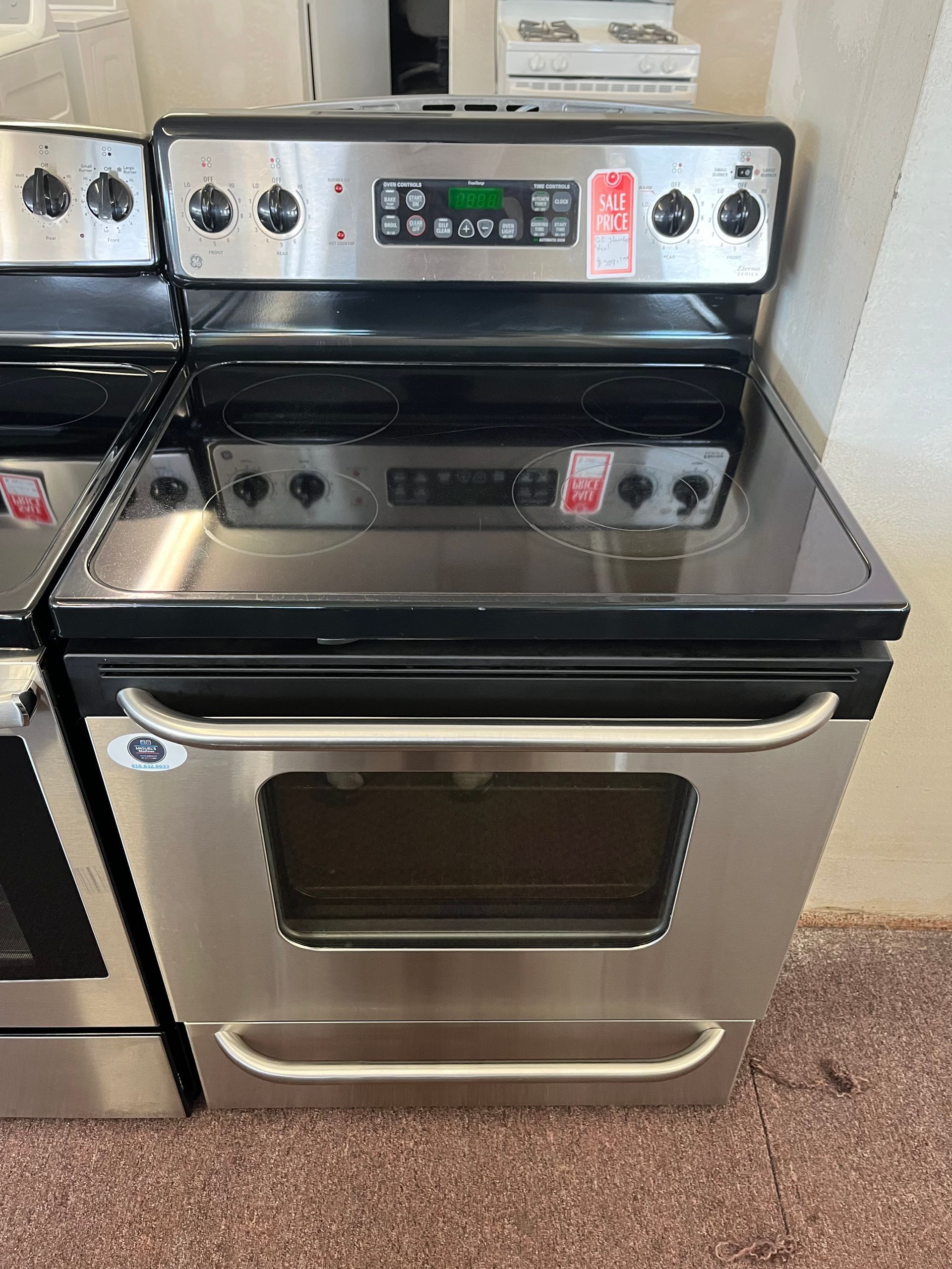 Front-loading silver LG washer with digital controls, shown in a laundry appliance showroom.