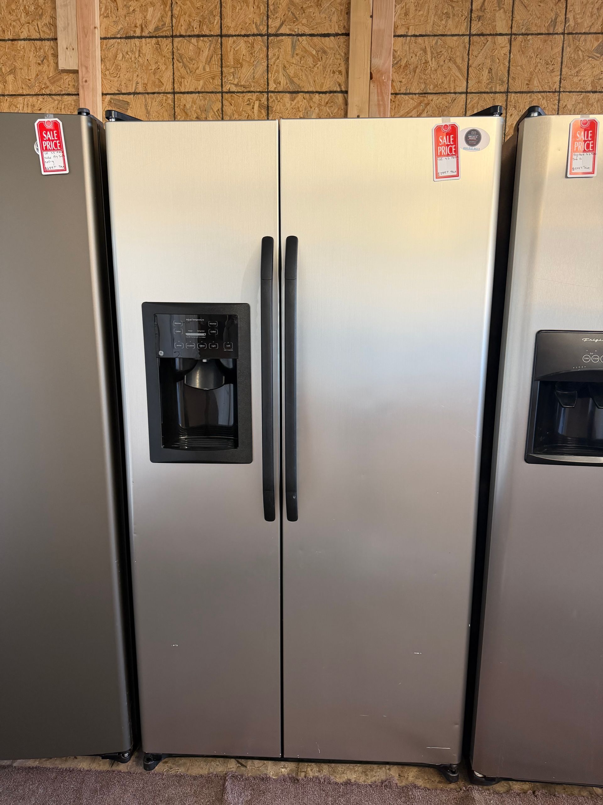 Stainless steel side-by-side refrigerator with water dispenser in a kitchen display row