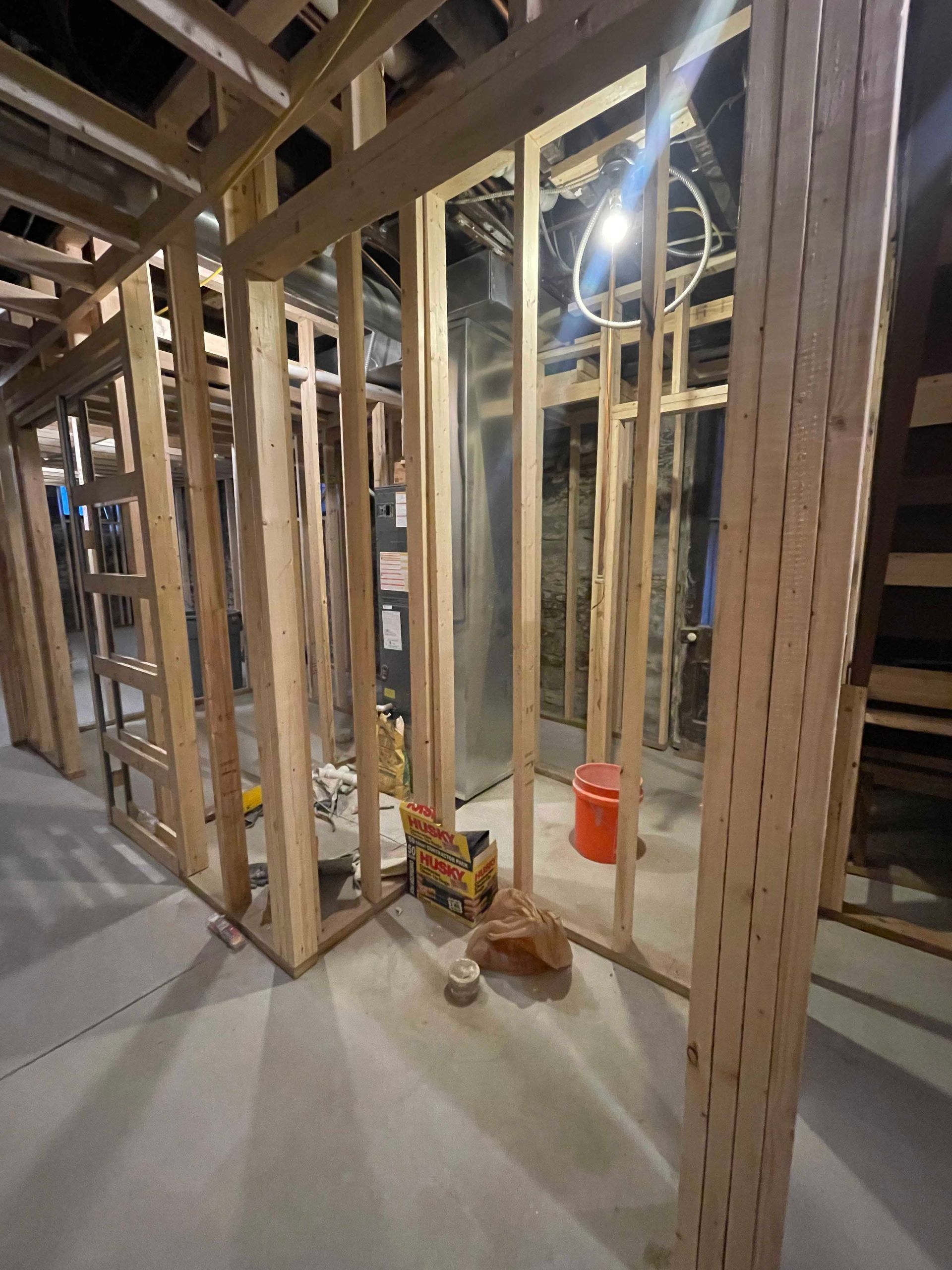 Basement framing with wooden studs, unfinished walls, and concrete floor.