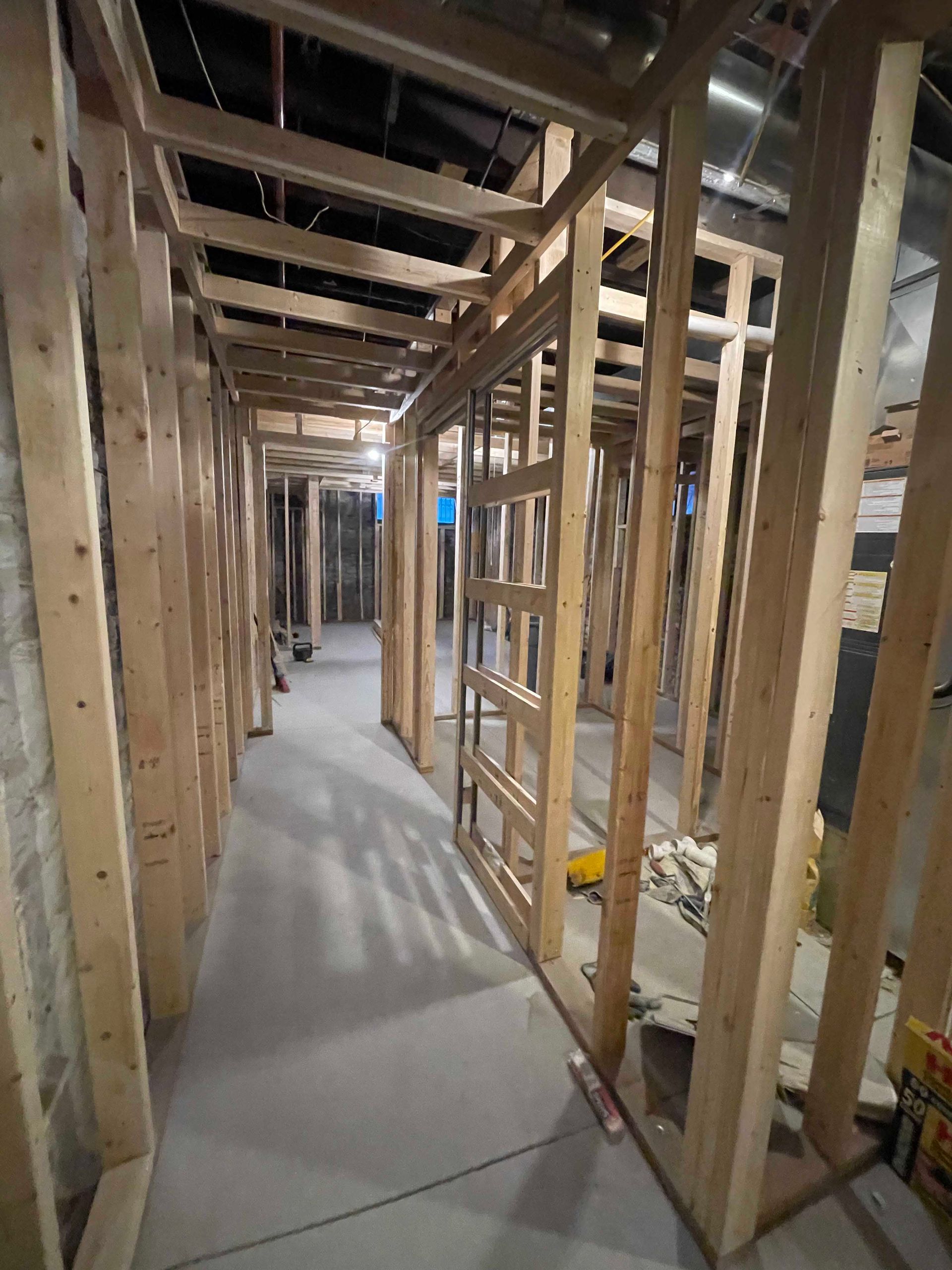 Interior hallway under construction; wooden framing, concrete floor.