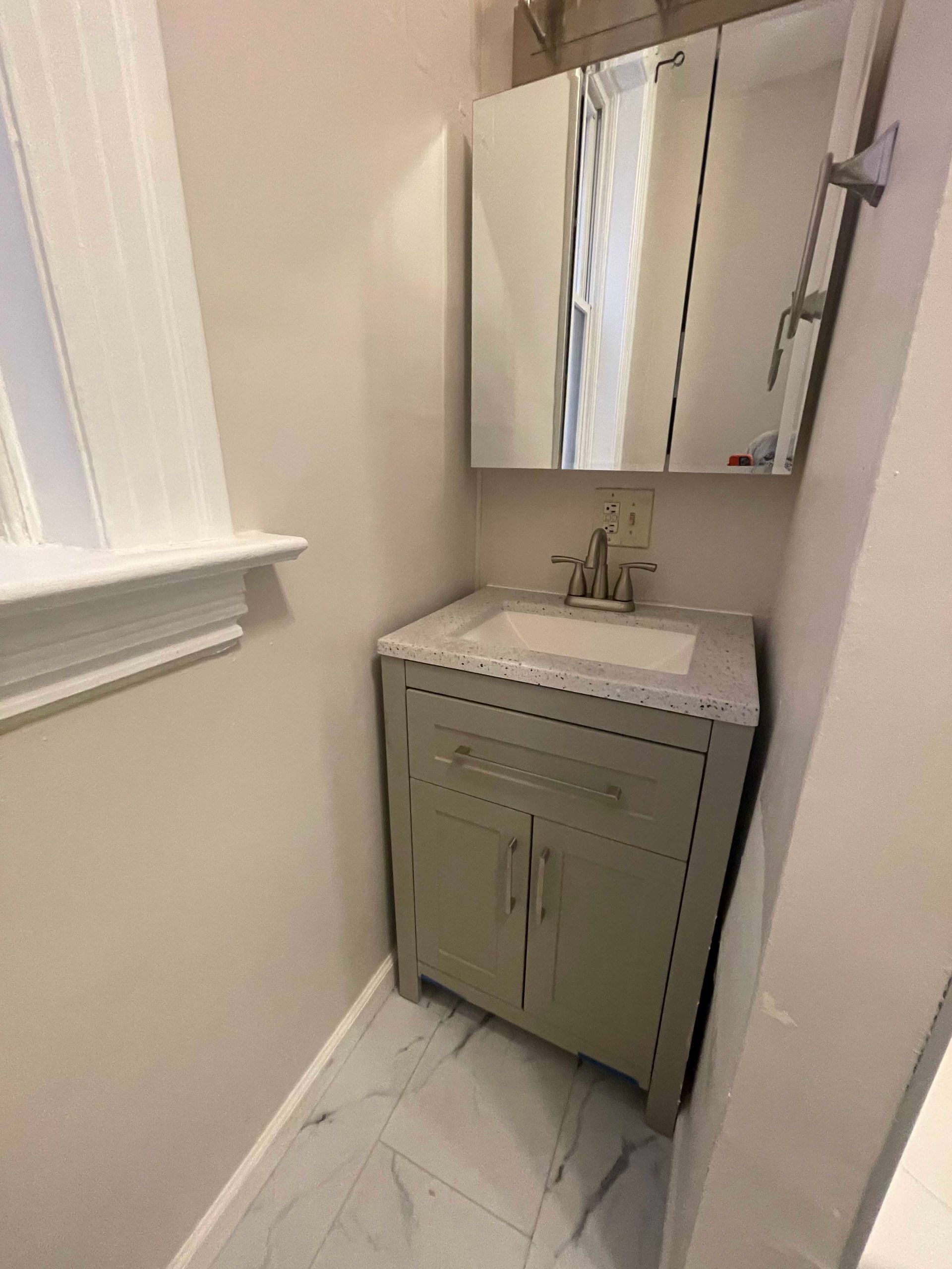 Small bathroom with a vanity, sink, and mirrored medicine cabinet.