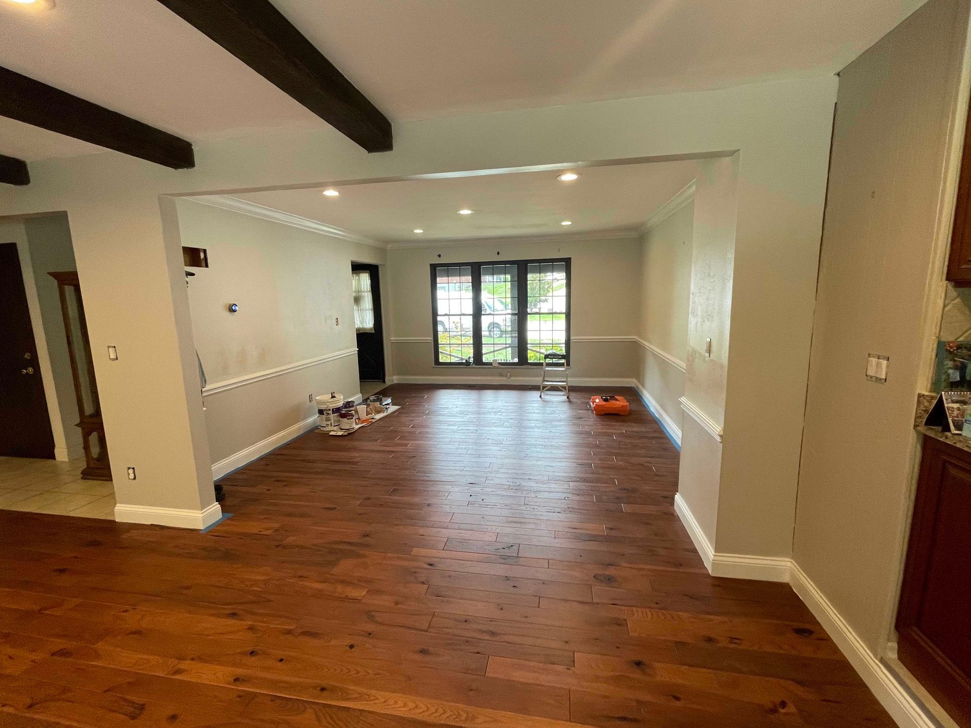 Empty room with newly painted gray walls, white trim, and dark wood floors, undergoing renovation.