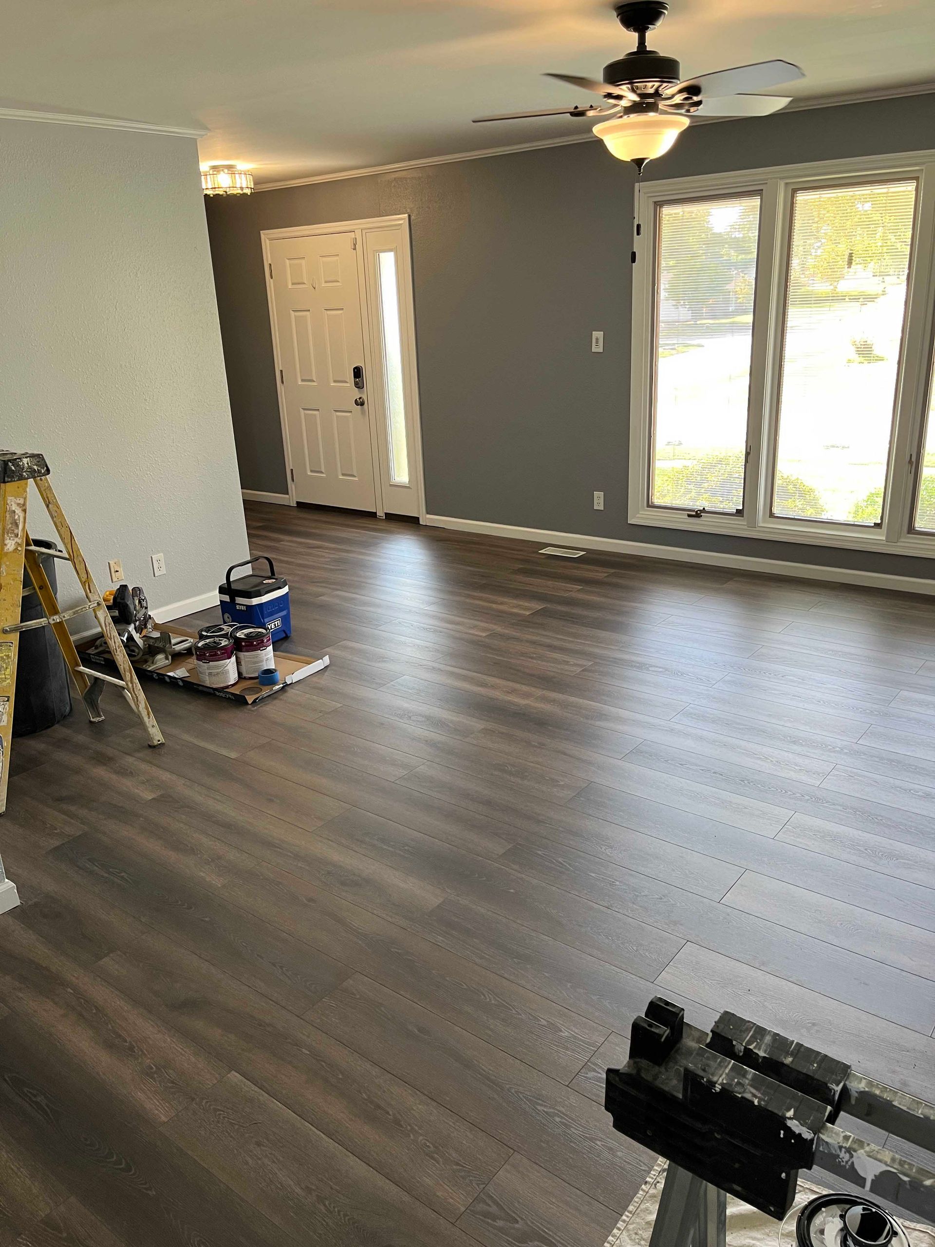 Living room with gray walls, dark wood floor, white trim, and a partially open white door.
