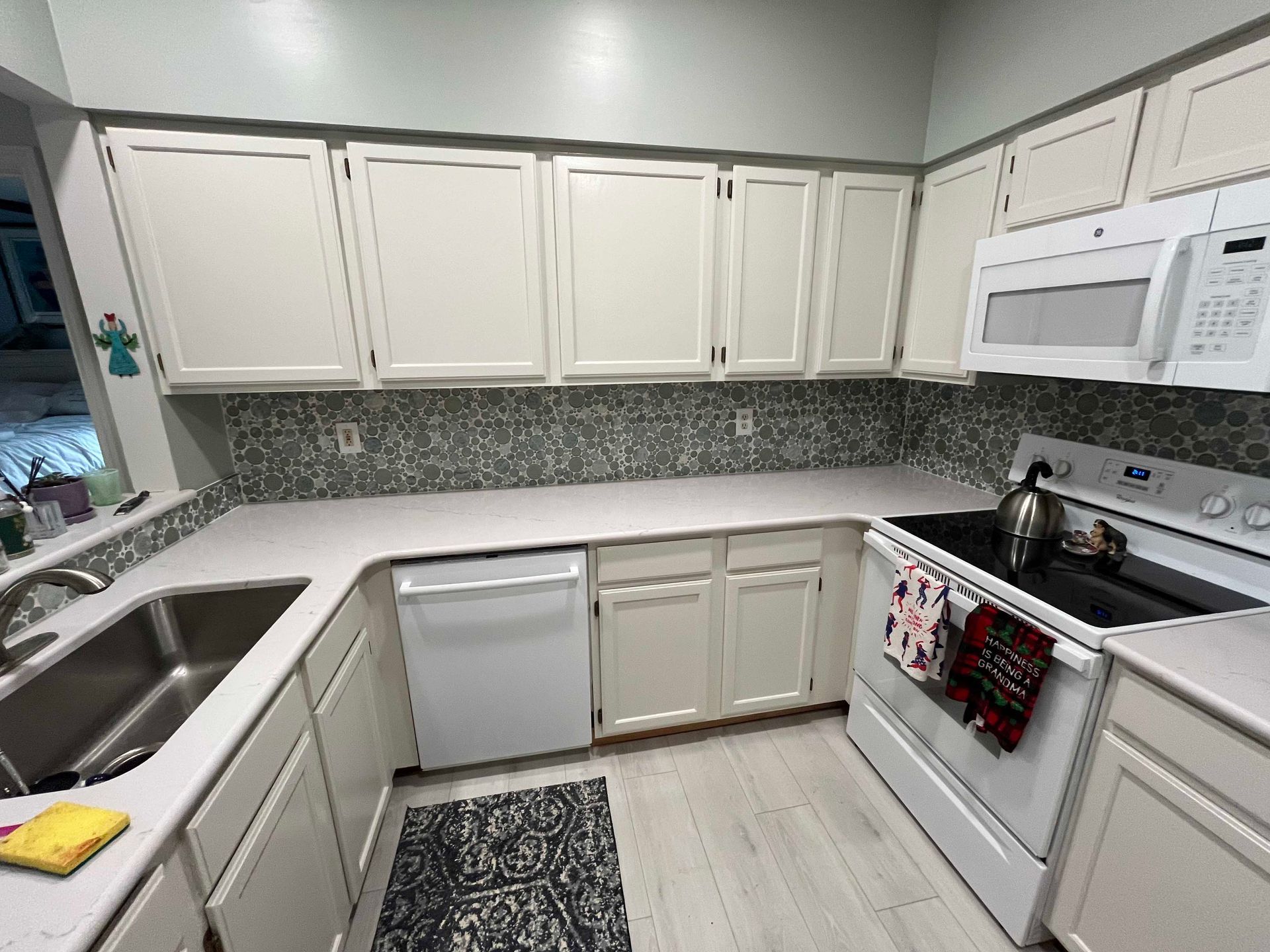 White kitchen with cabinets, appliances, and patterned backsplash.