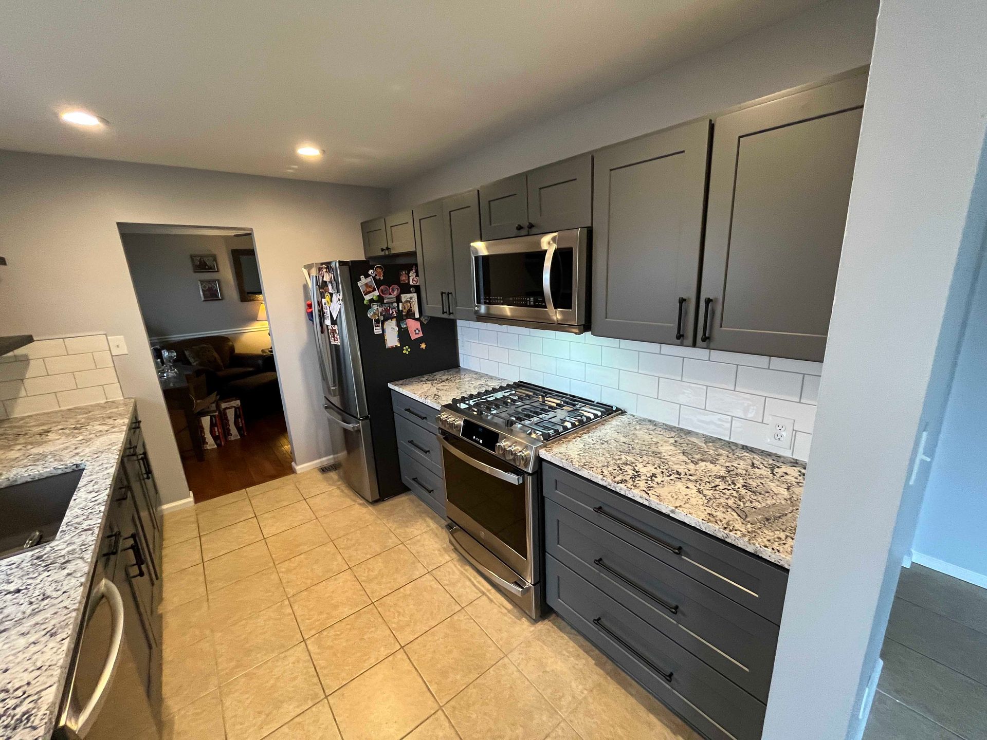 Gray kitchen with granite countertops, stainless steel appliances, and tile backsplash.