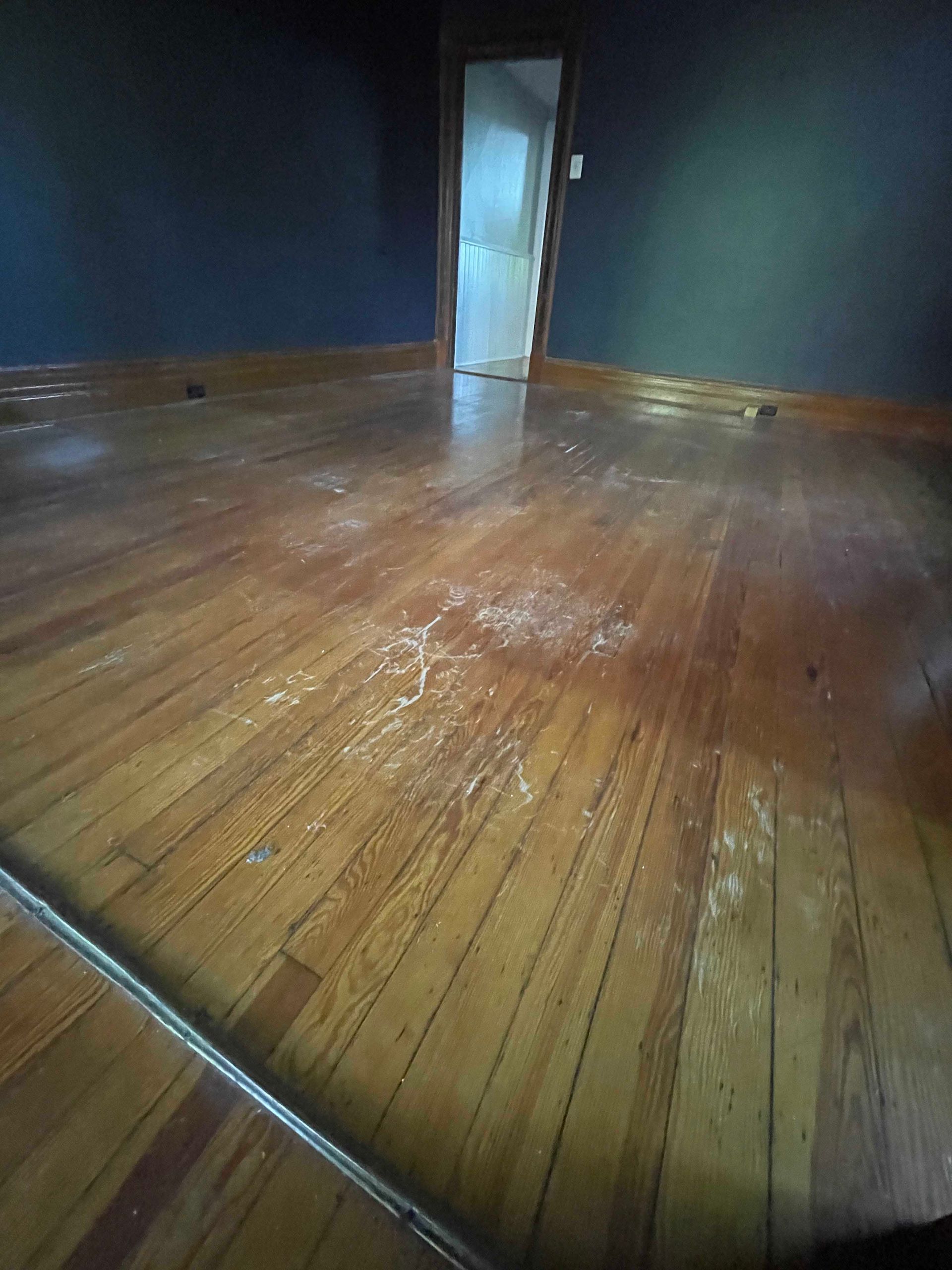 Wooden floor with scattered debris, blue walls, and a doorway.