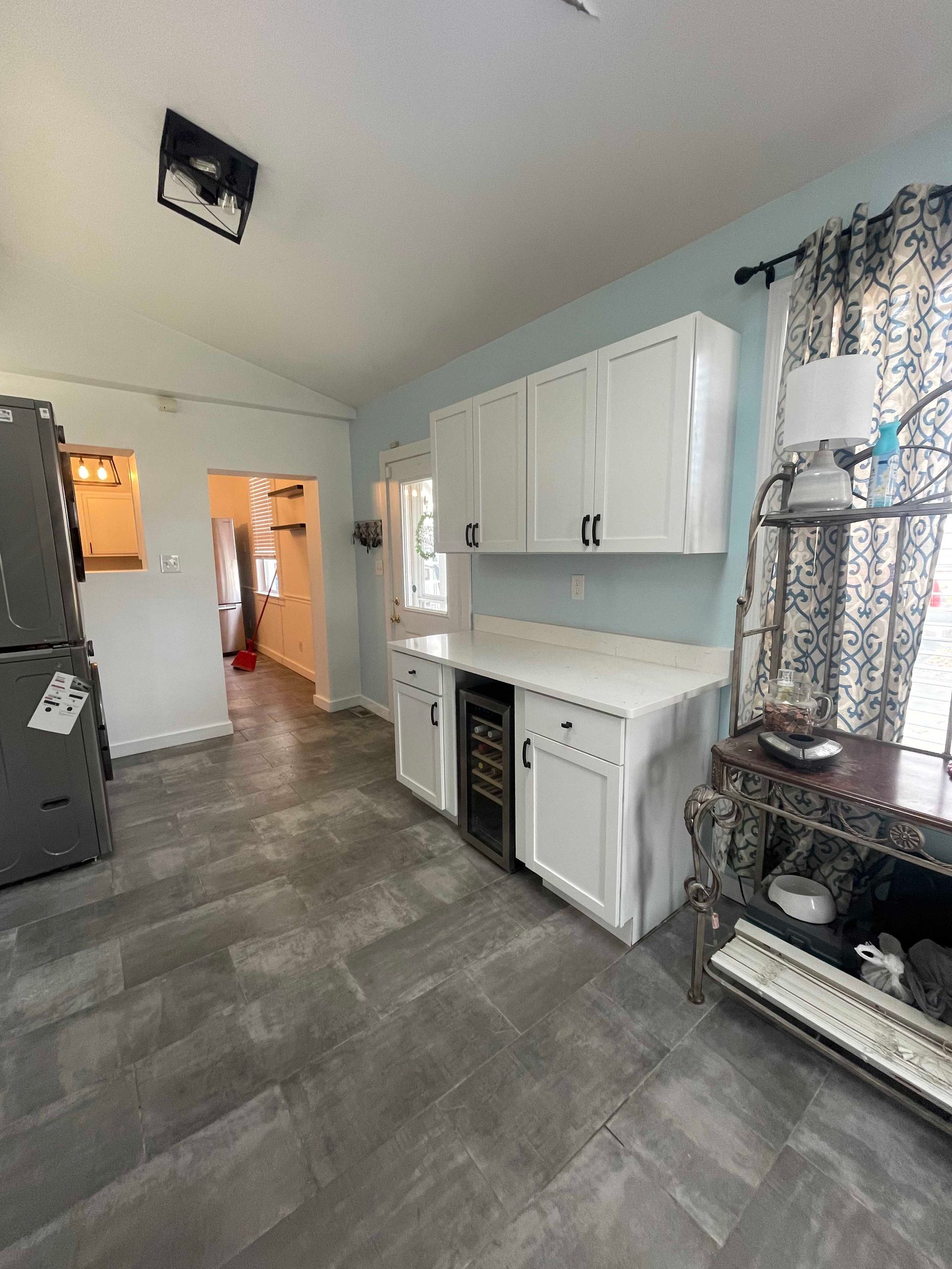 Kitchen with white cabinets, wine cooler, blue walls, and gray tile floor.