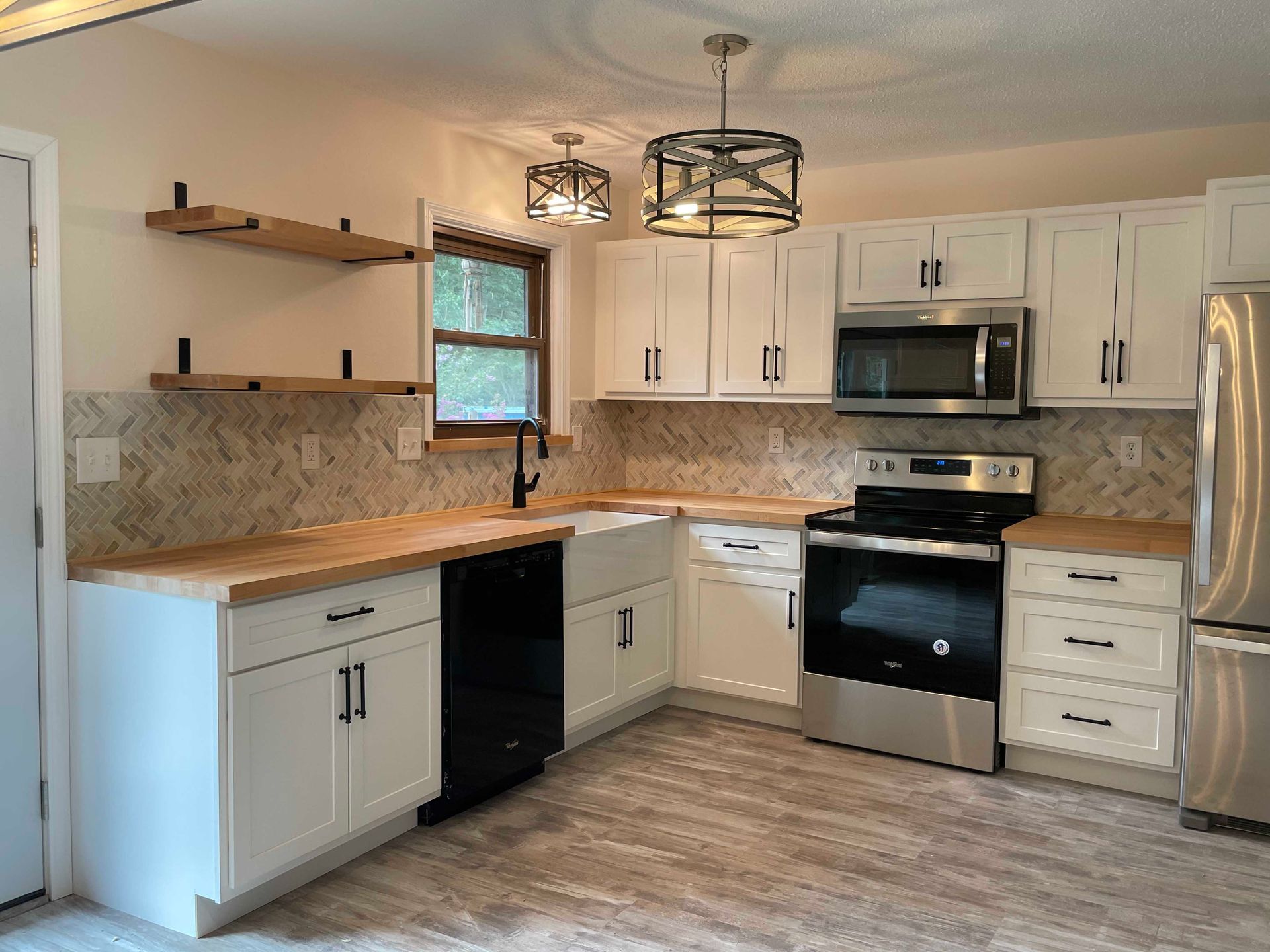 White kitchen with wooden countertops, stainless steel appliances, and decorative lighting.