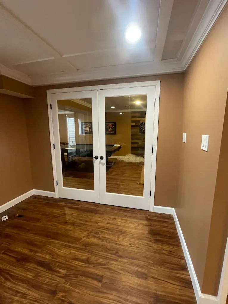 French doors in a room with brown walls and wood-look flooring.