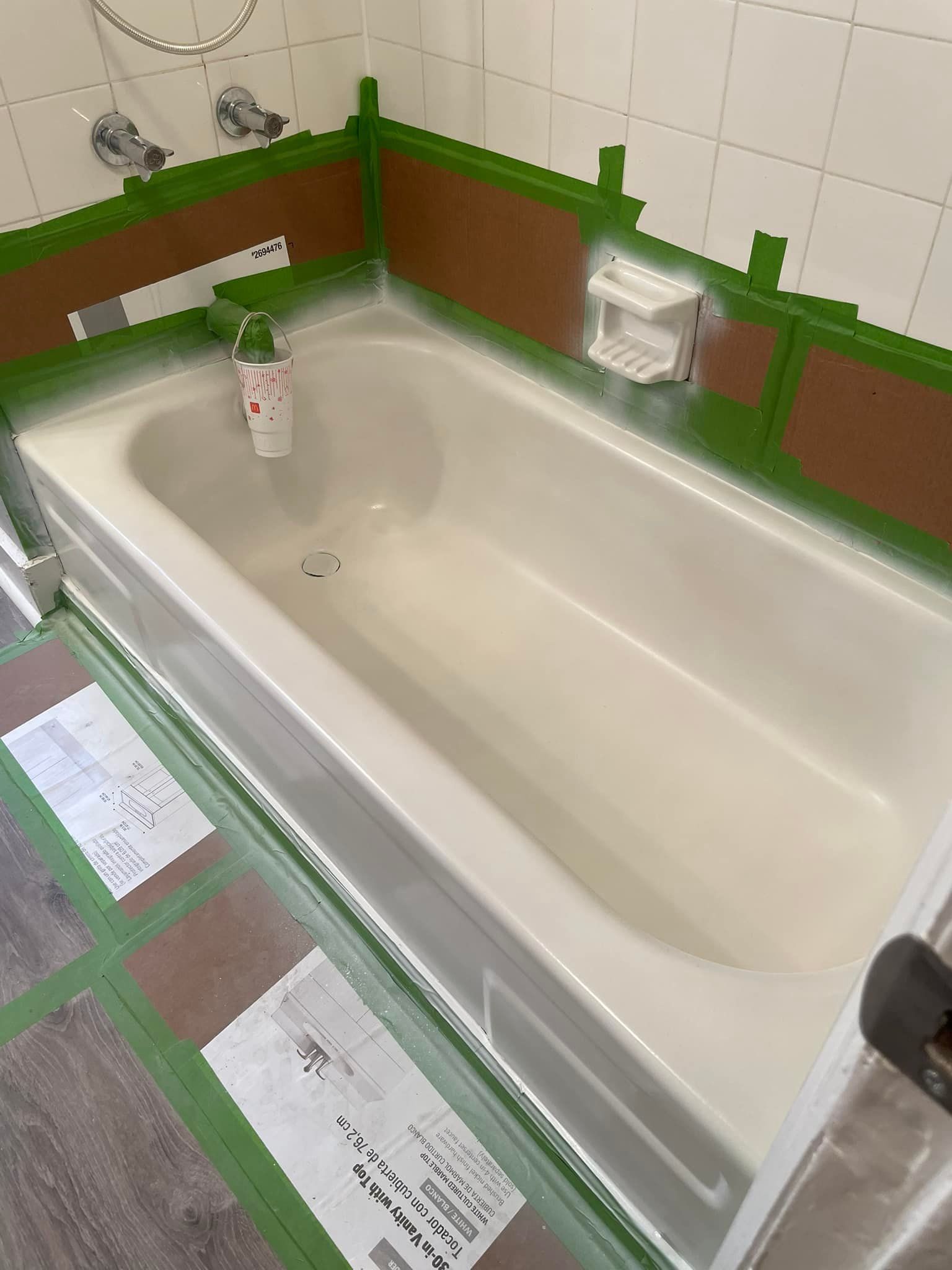 Bathtub being refinished, brown tape protects the tile walls and floor from paint.