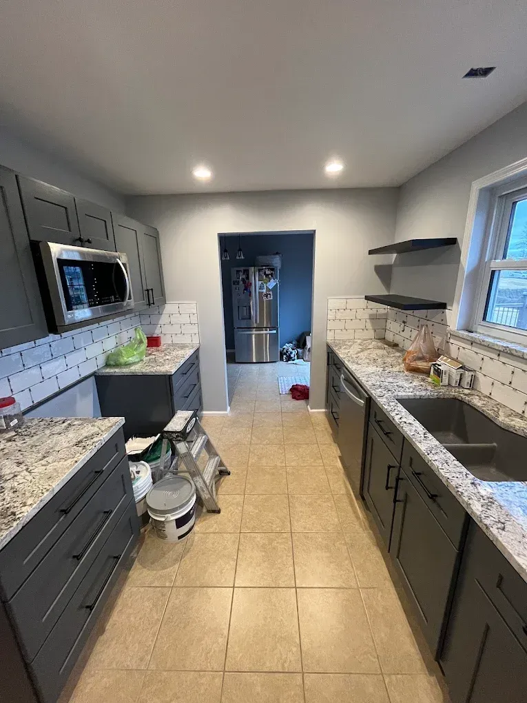 Gray kitchen with granite countertops, tiled backsplash, and stainless steel appliances.