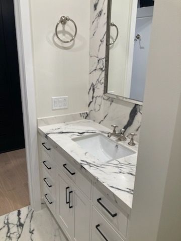 A bathroom with a sink, mirror, and marble counter top.