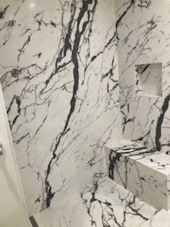 A bathroom with a black and white marble shower wall.