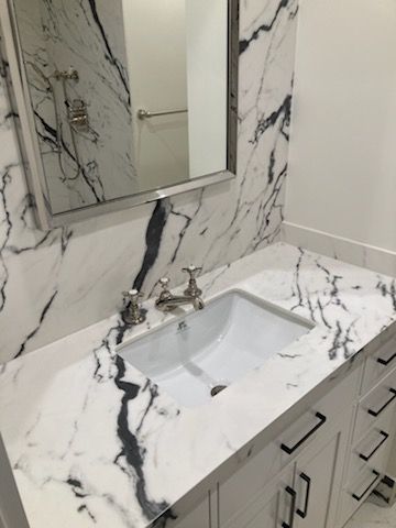 A bathroom with a sink, mirror and marble counter top.