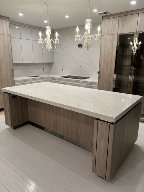 a kitchen with a large island and a chandelier hanging from the ceiling