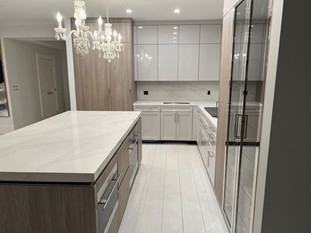 a kitchen with a large island in the middle and a chandelier hanging from the ceiling