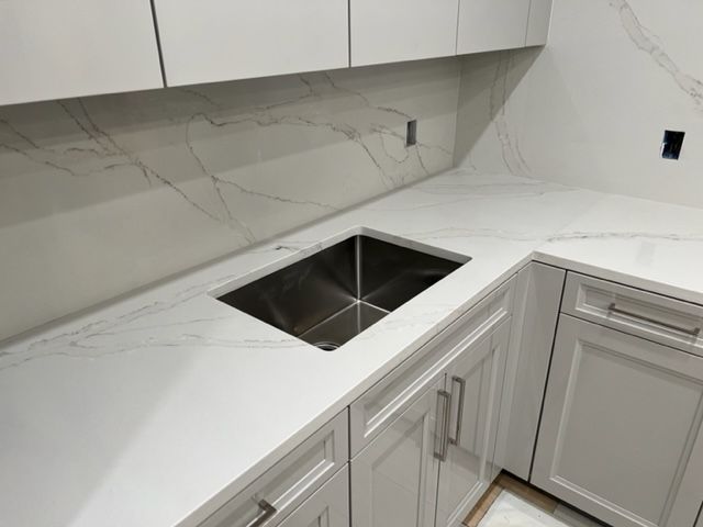 a kitchen with white cabinets and a stainless steel sink