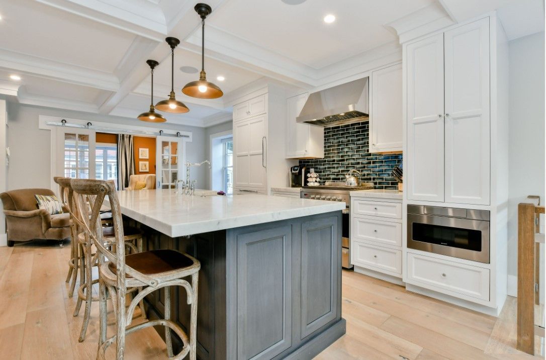 a kitchen with white cabinets, stainless steel appliances, a large island and stools