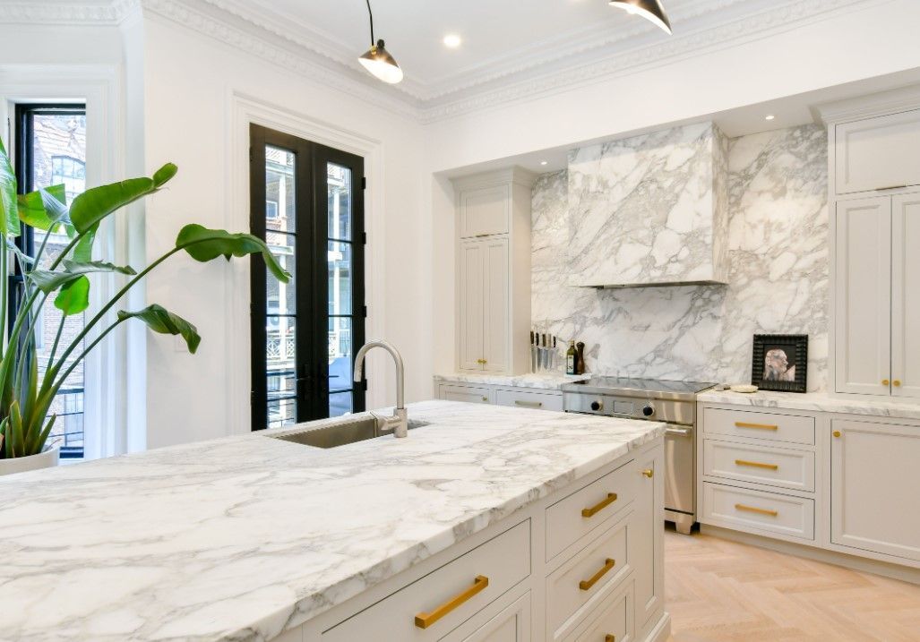 a kitchen with white cabinets and marble counter tops