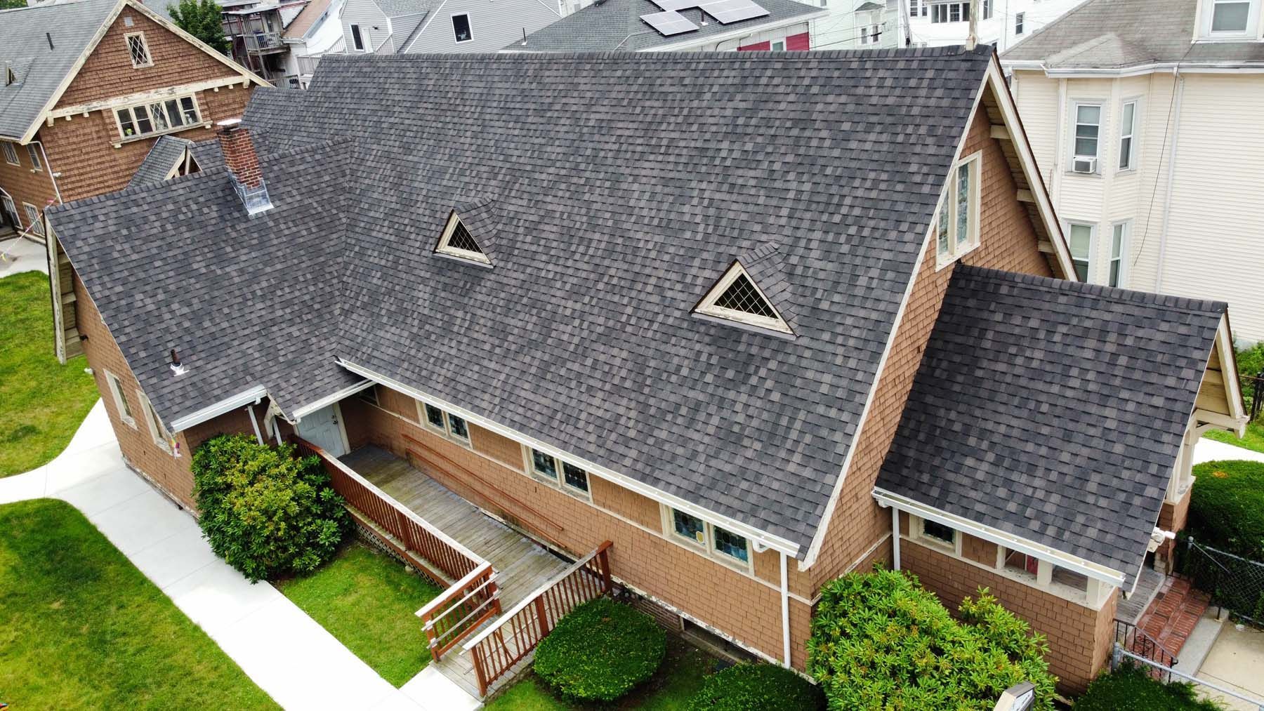 An aerial view of a large brick house with a black roof.