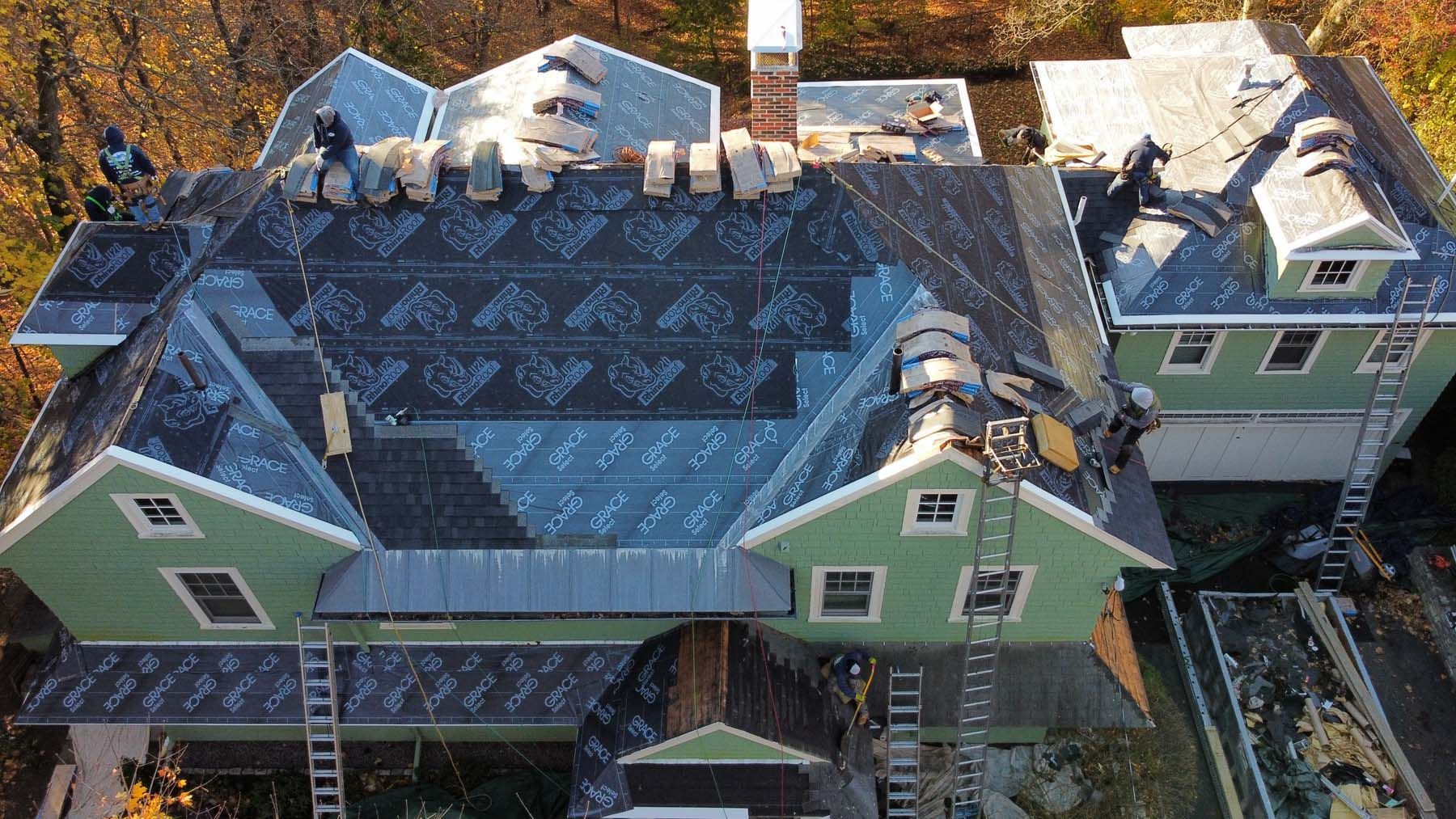 An aerial view of a large house with a roof being installed.