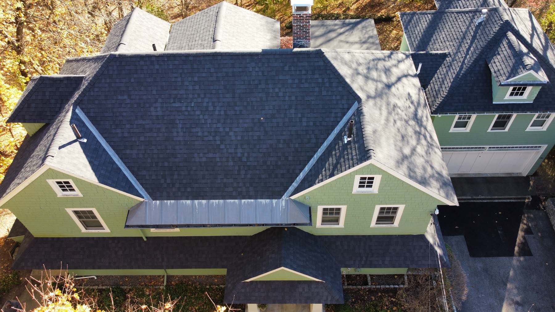 An aerial view of a green house with a black roof