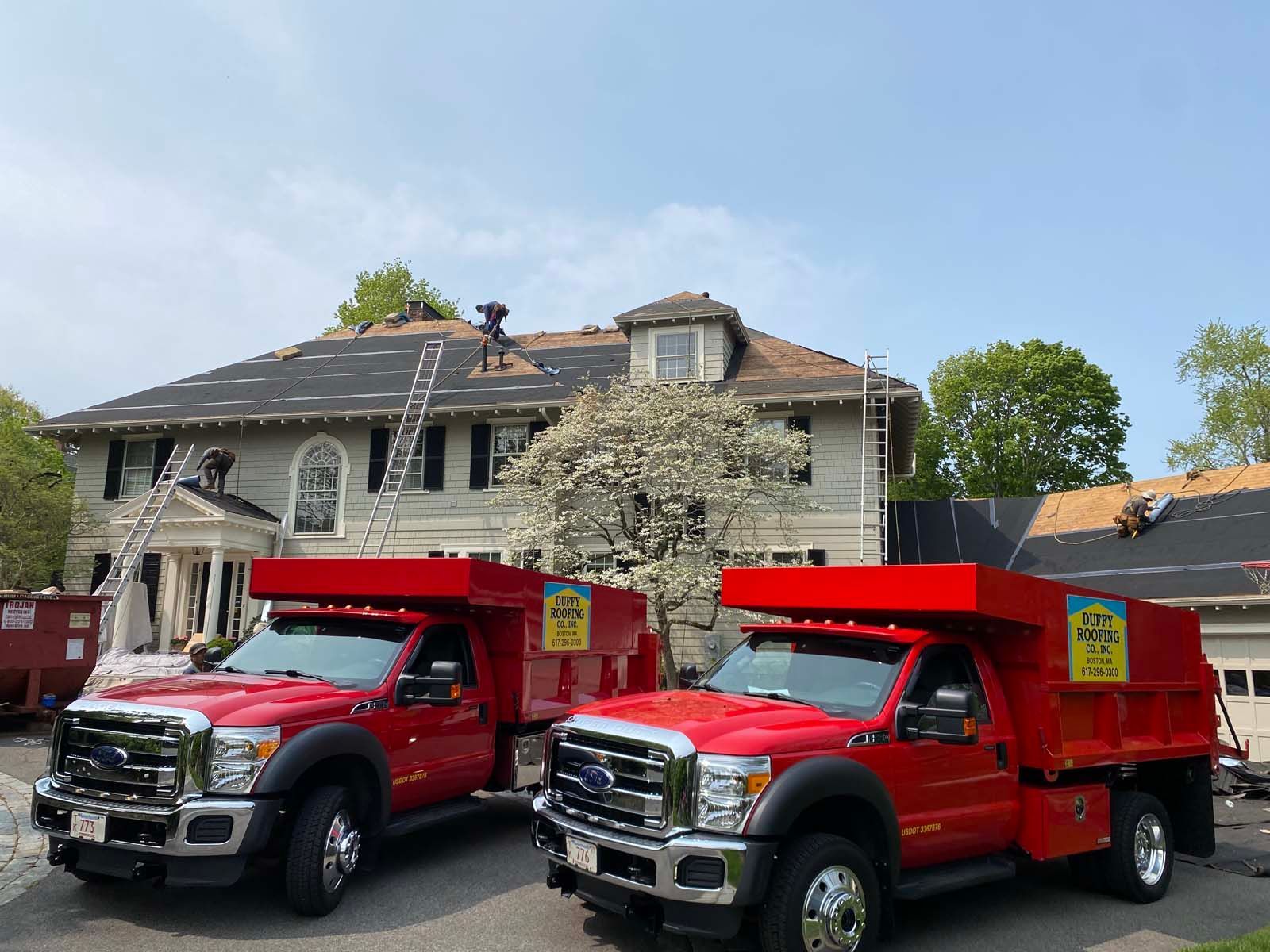 Two red trucks are parked in front of a house.