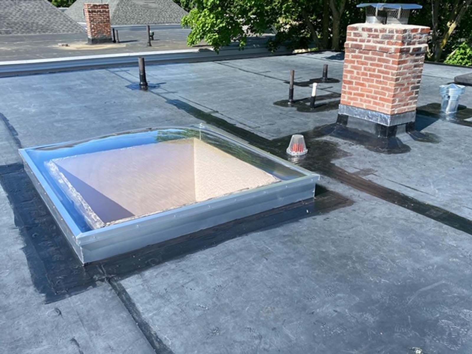 A roof with a skylight and a chimney on it