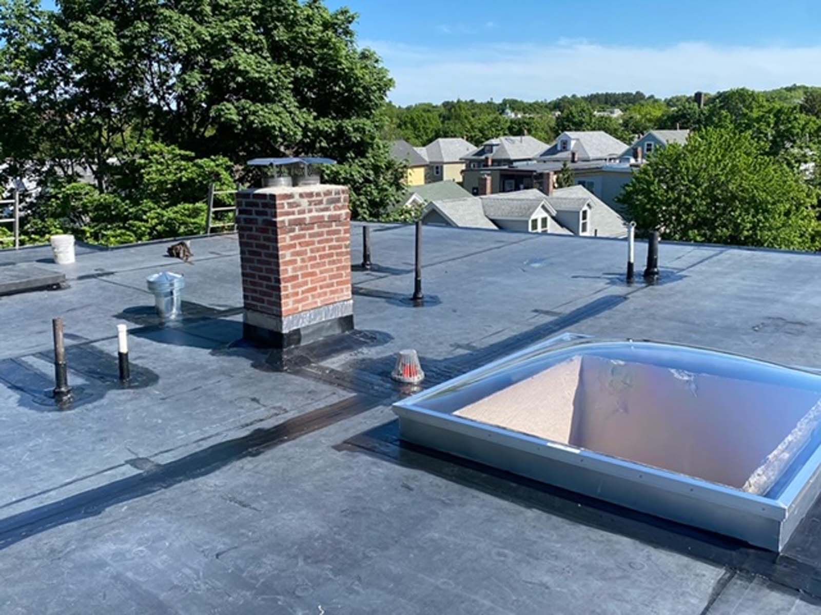 A roof with a chimney and a skylight on it.