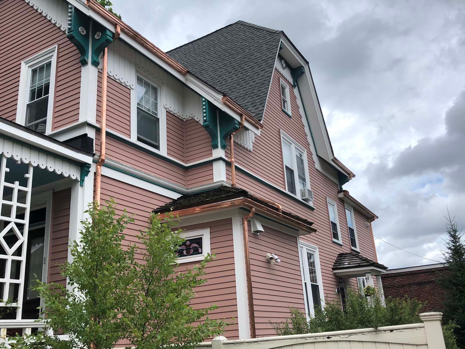 A large pink house with a copper gutter on the side