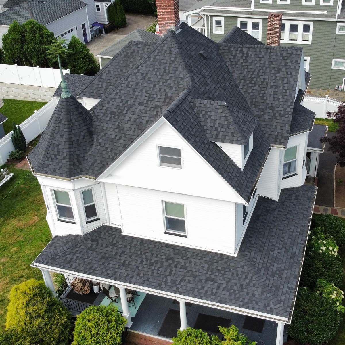 An aerial view of a white house with a black roof