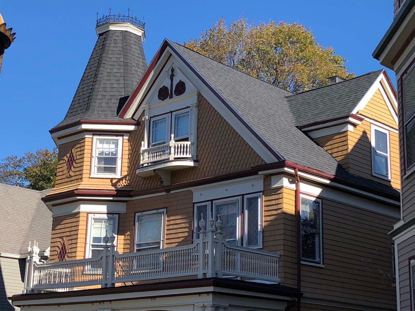 A large brick house with a gray roof and a balcony