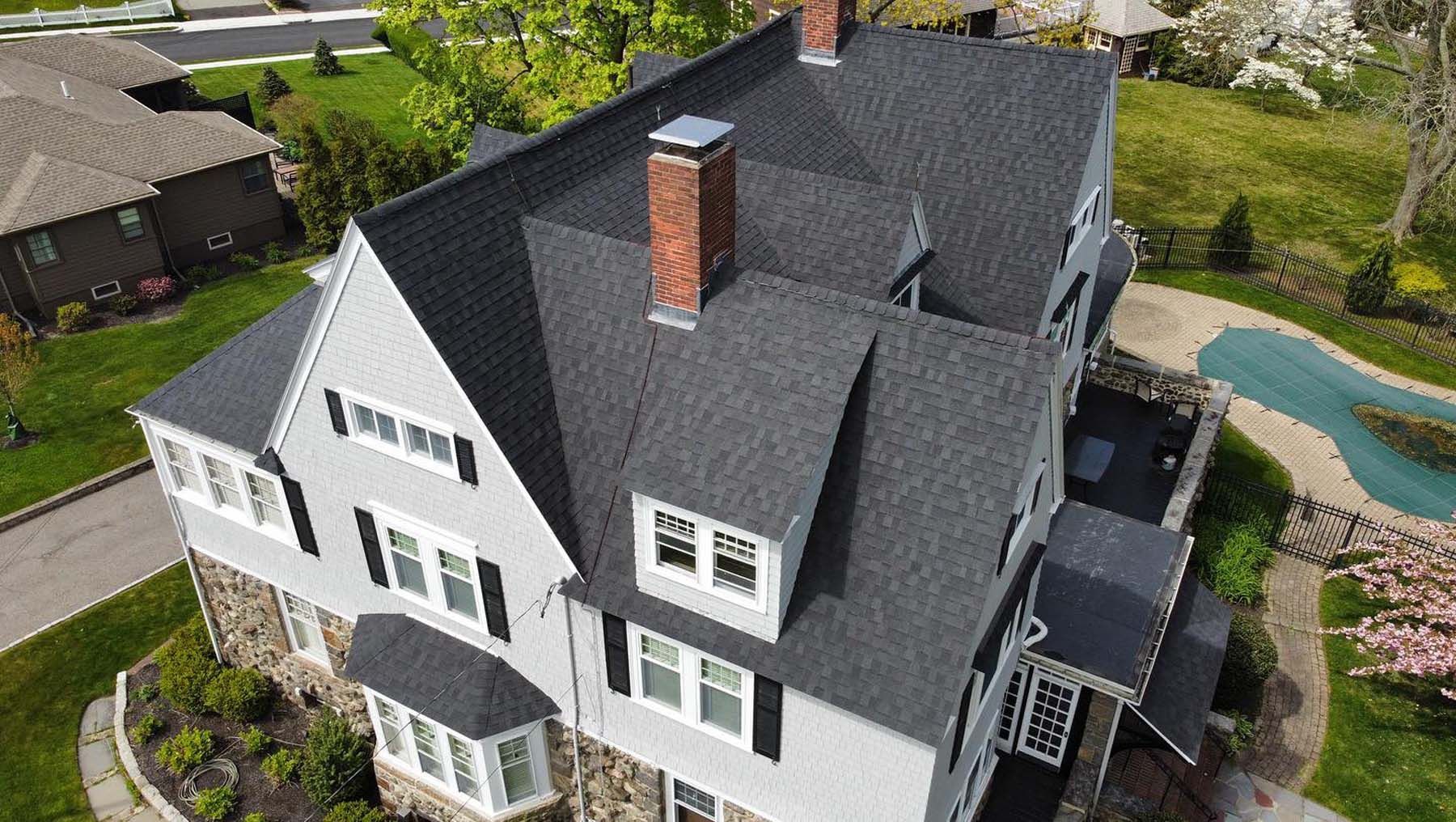 An aerial view of a large white house with a black roof.