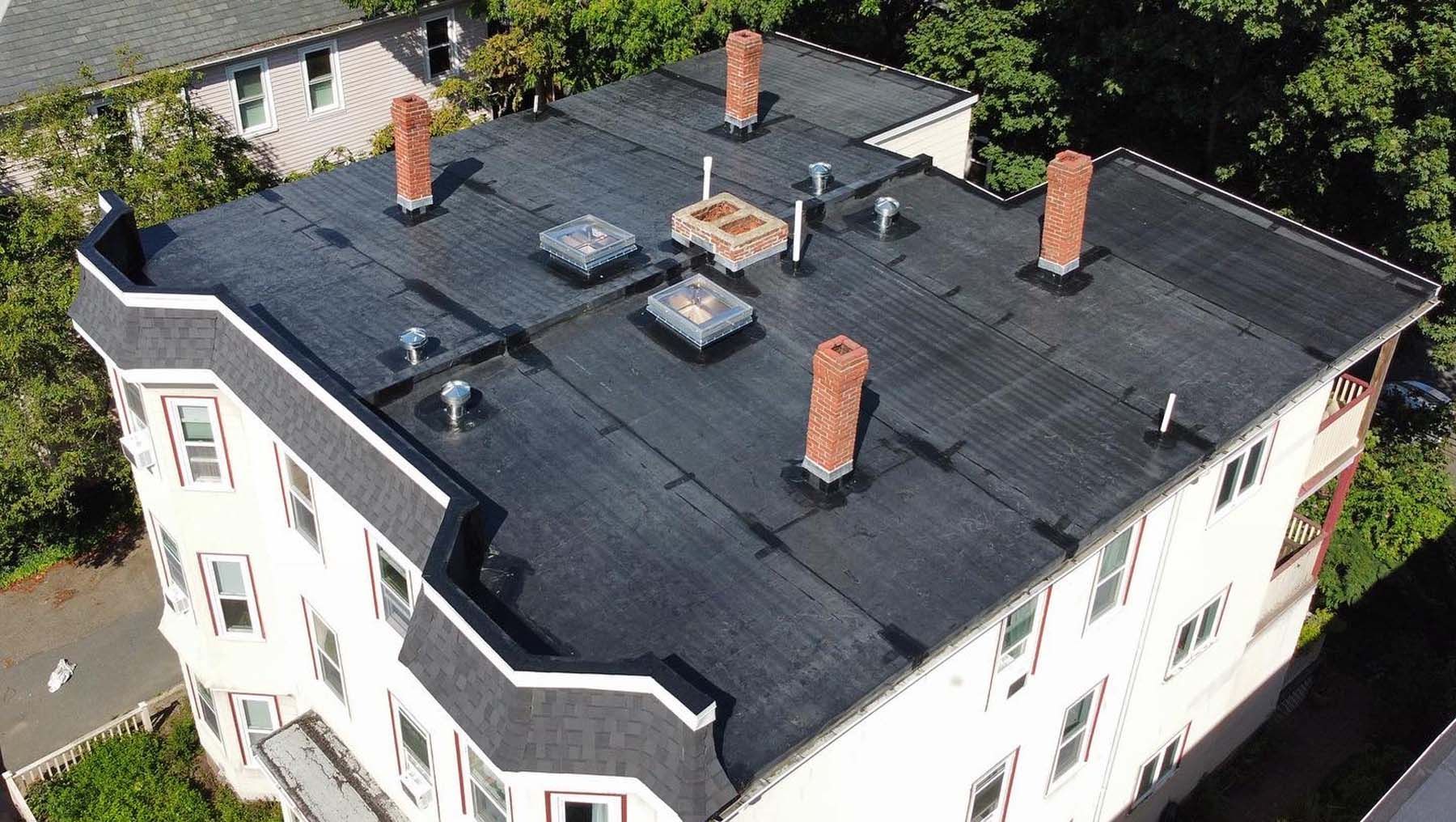 An aerial view of a building with a flat roof and chimneys.