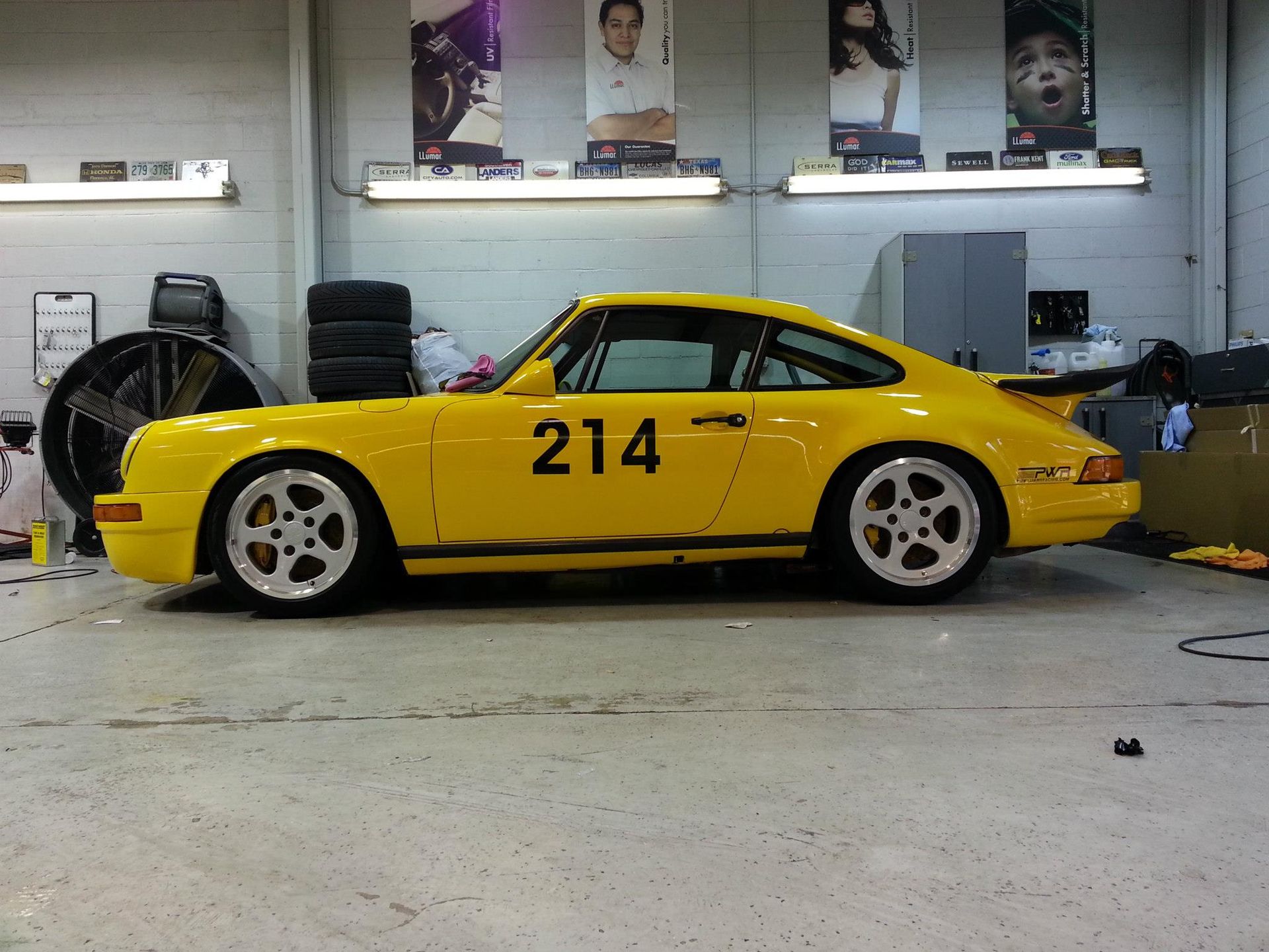 A yellow car with the number 214 on the side is parked in a garage.