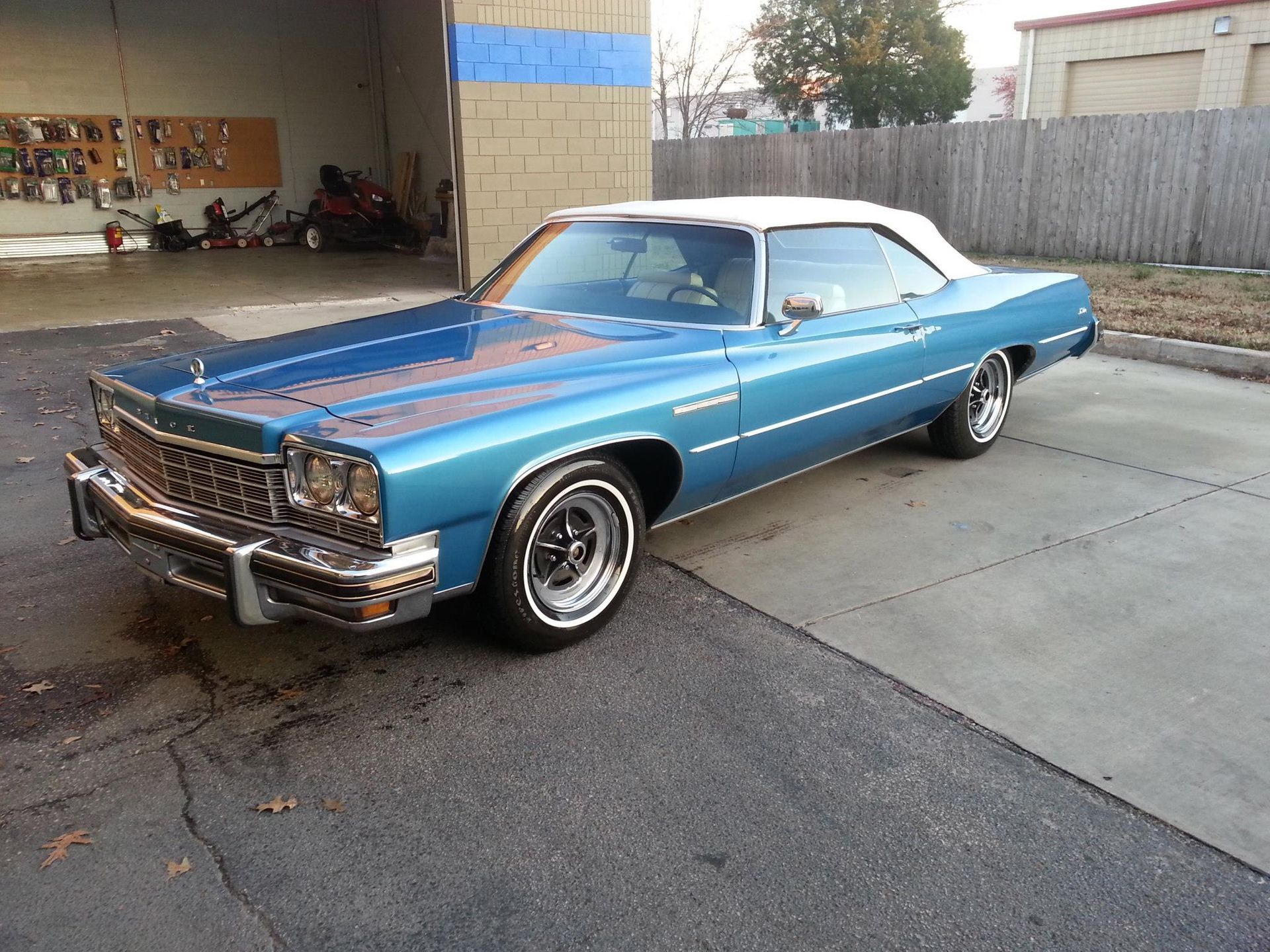 A blue car with a white top is parked in a parking lot.