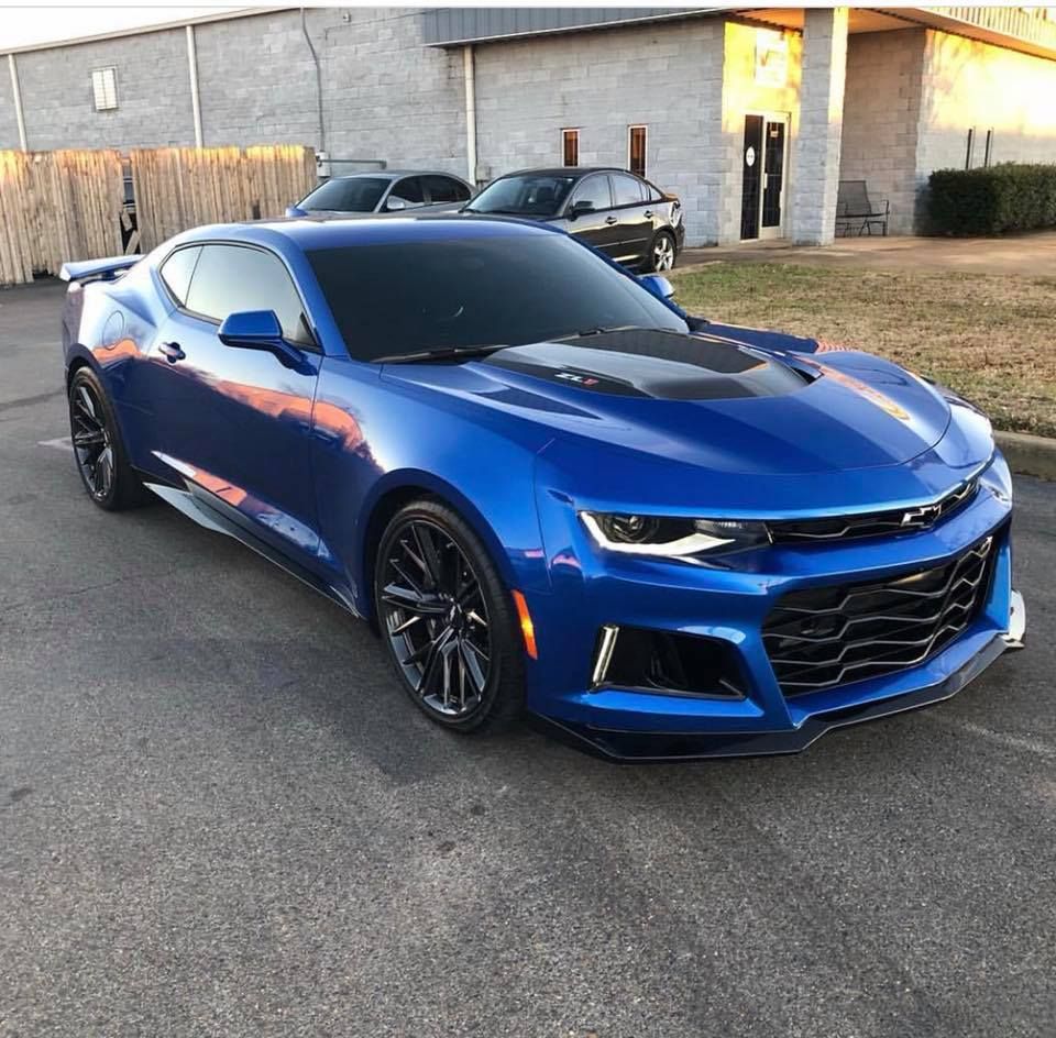 A blue car is parked in front of a building.